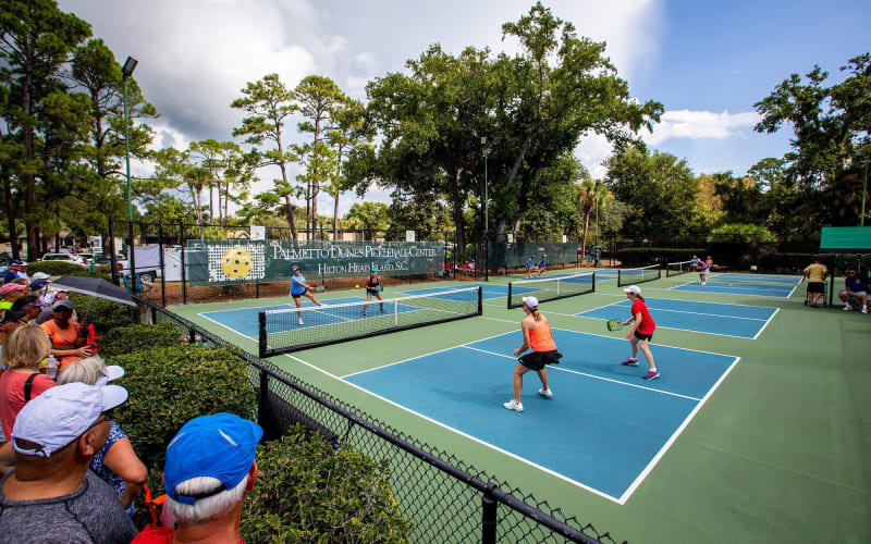 People playing on pickleball courts with crowd watching