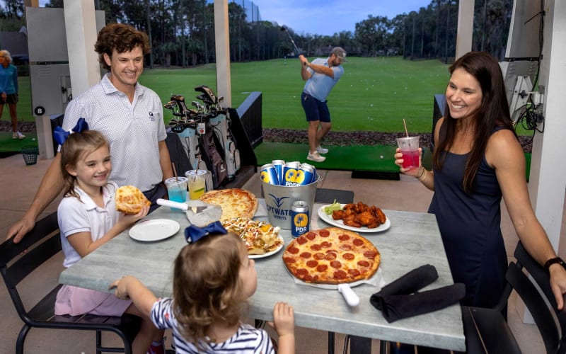 family enjoying pizza and drinks at Toptracer