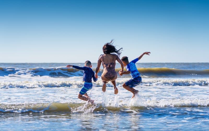 Family jumping into waves on beach