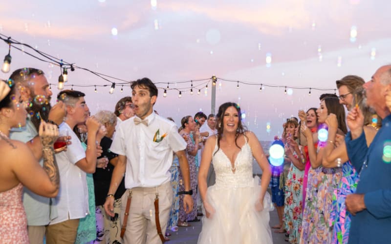 Wedding couple with bubbles sail off at the beach