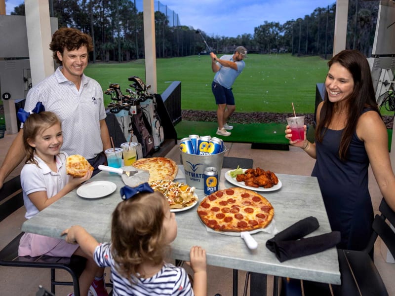 family enjoying pizza and drinks at Toptracer