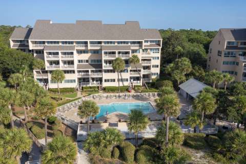 Aerial view of community pool and building with beach access at Captain's Walk