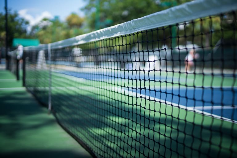 close up of the net against the green and blue of the tennis courts