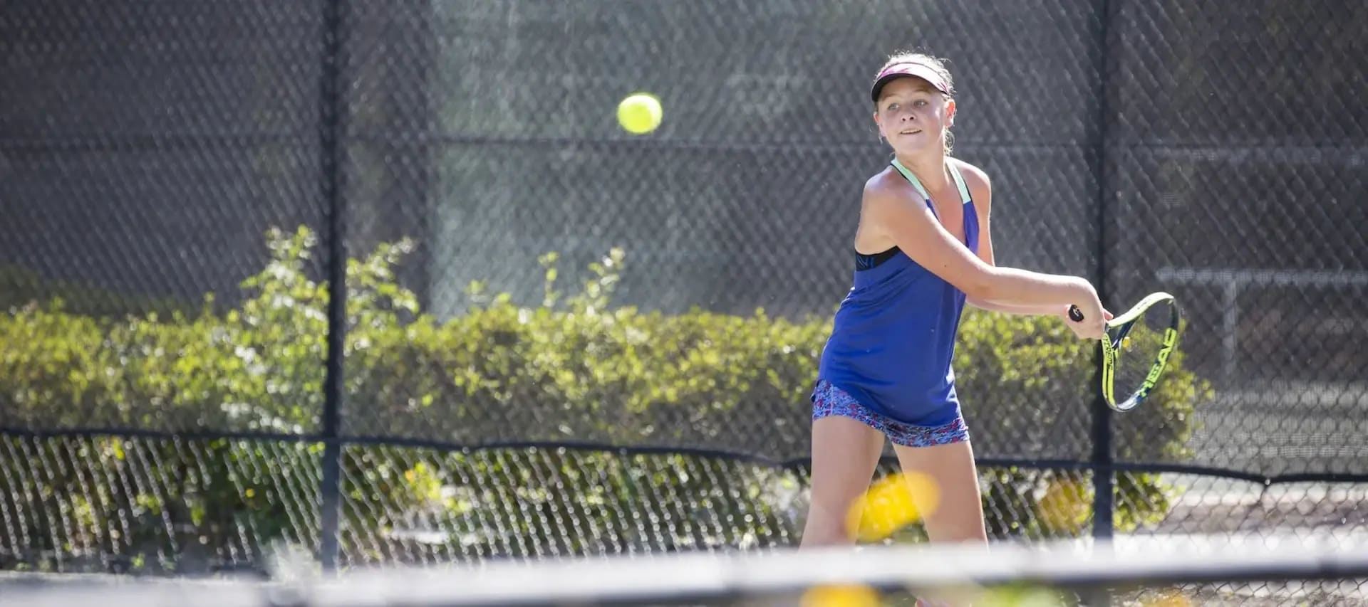 a young girl mid swing playing tennis at Palmetto Dunes Tennis center