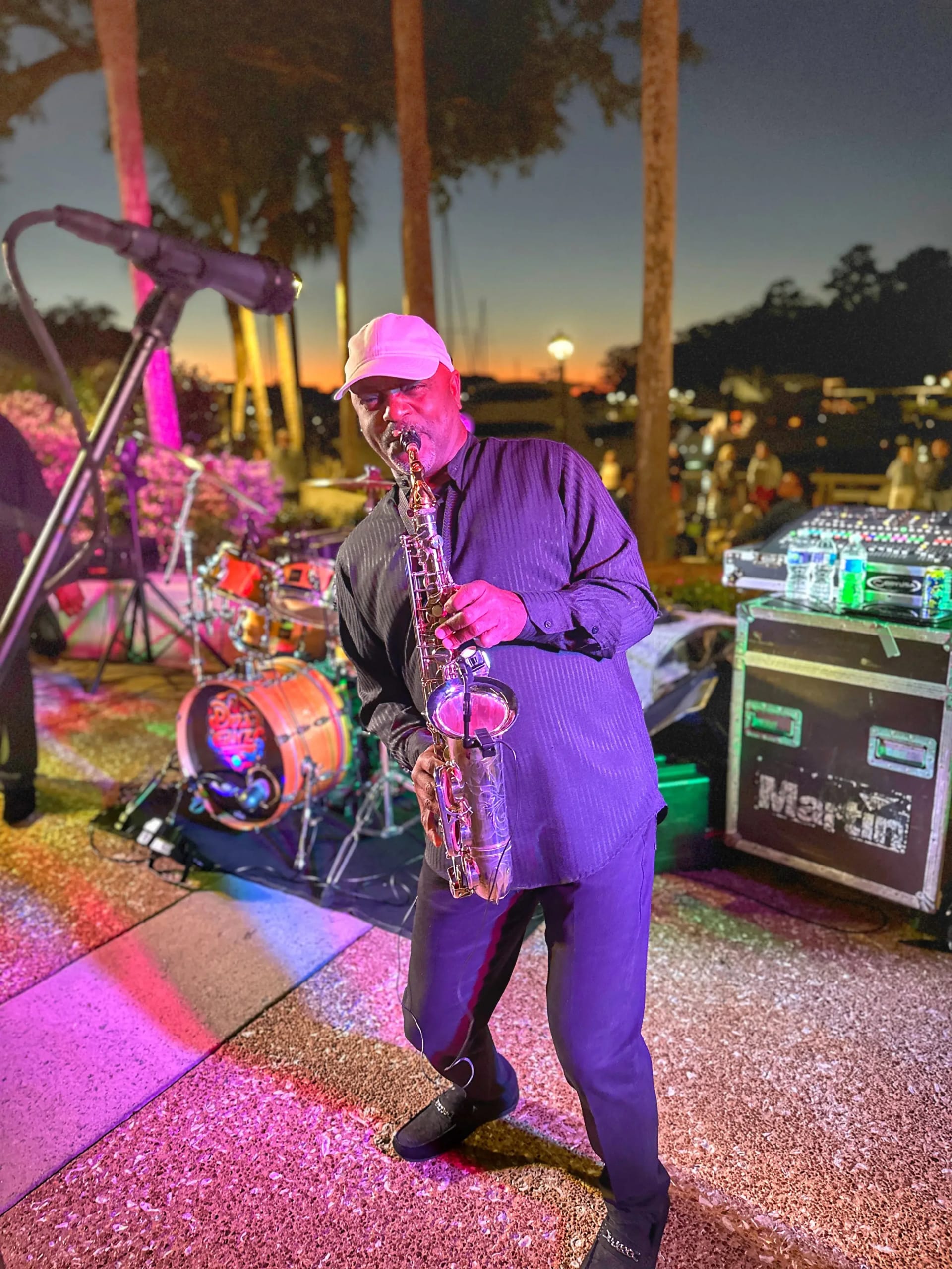 man playing a saxophone at night along the marina