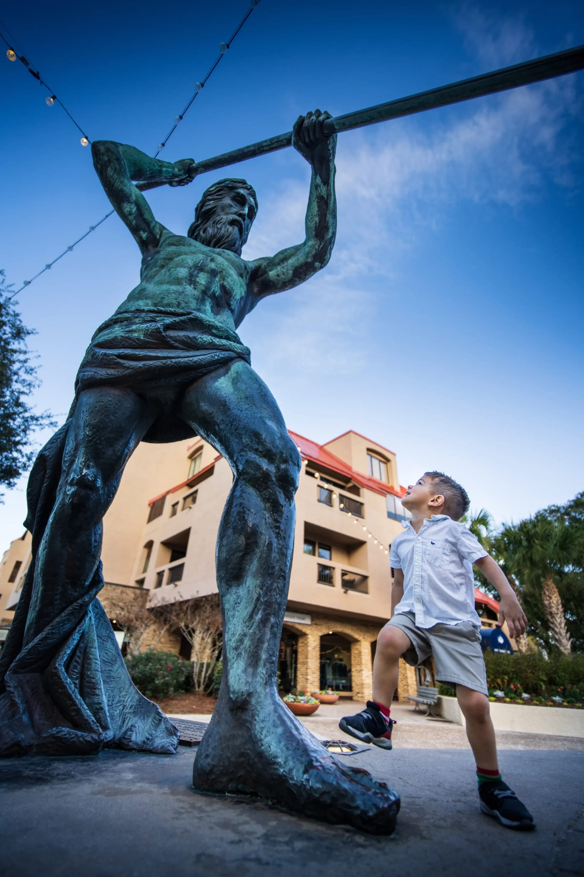 boy staring up at the tall neptune statue