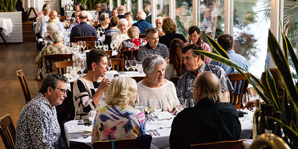 group of diners fill tables along the window in Alexander's sunroom for a wine dinner event
