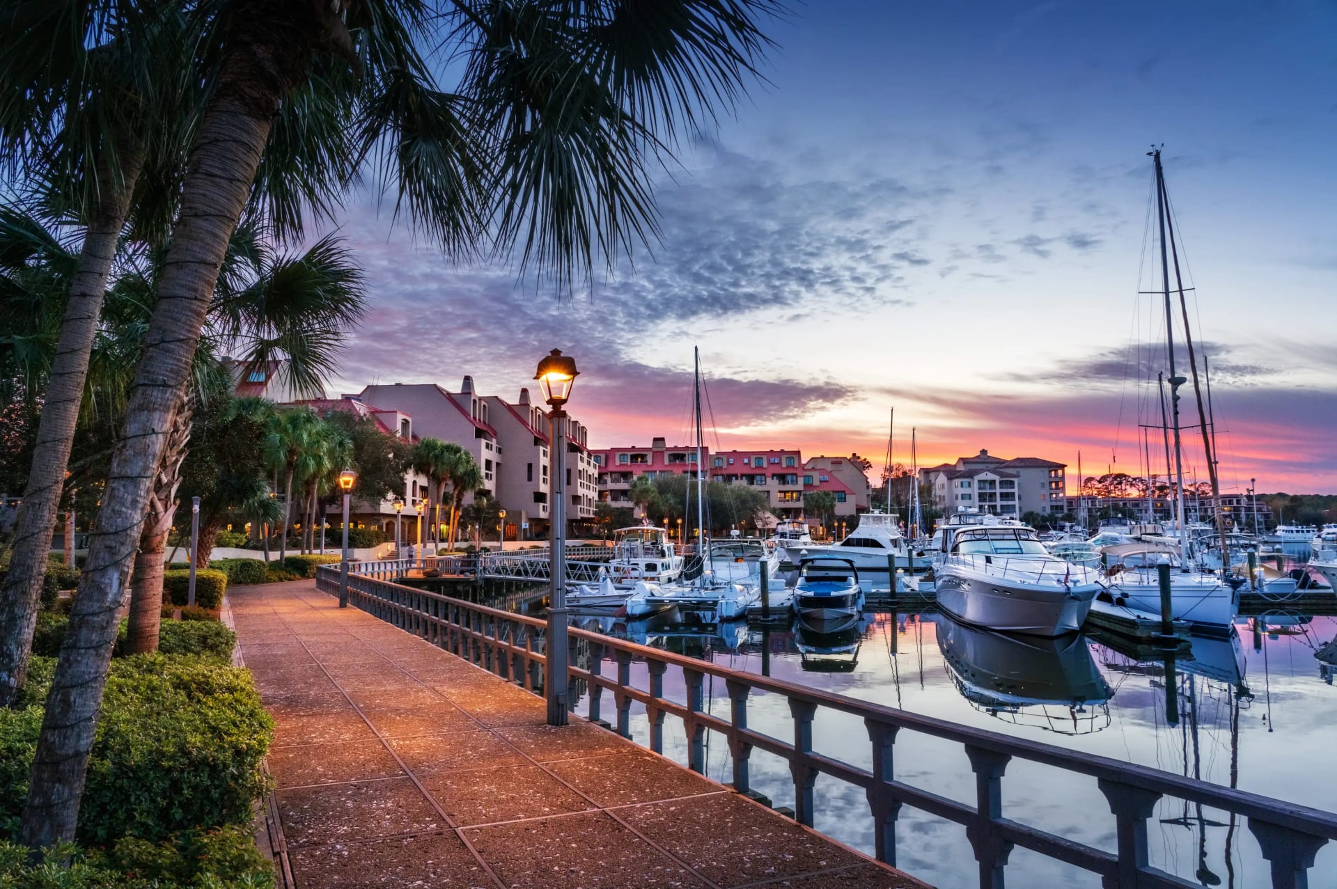 waterfront walkway along the marina filled with boats under pastel skies at sunset