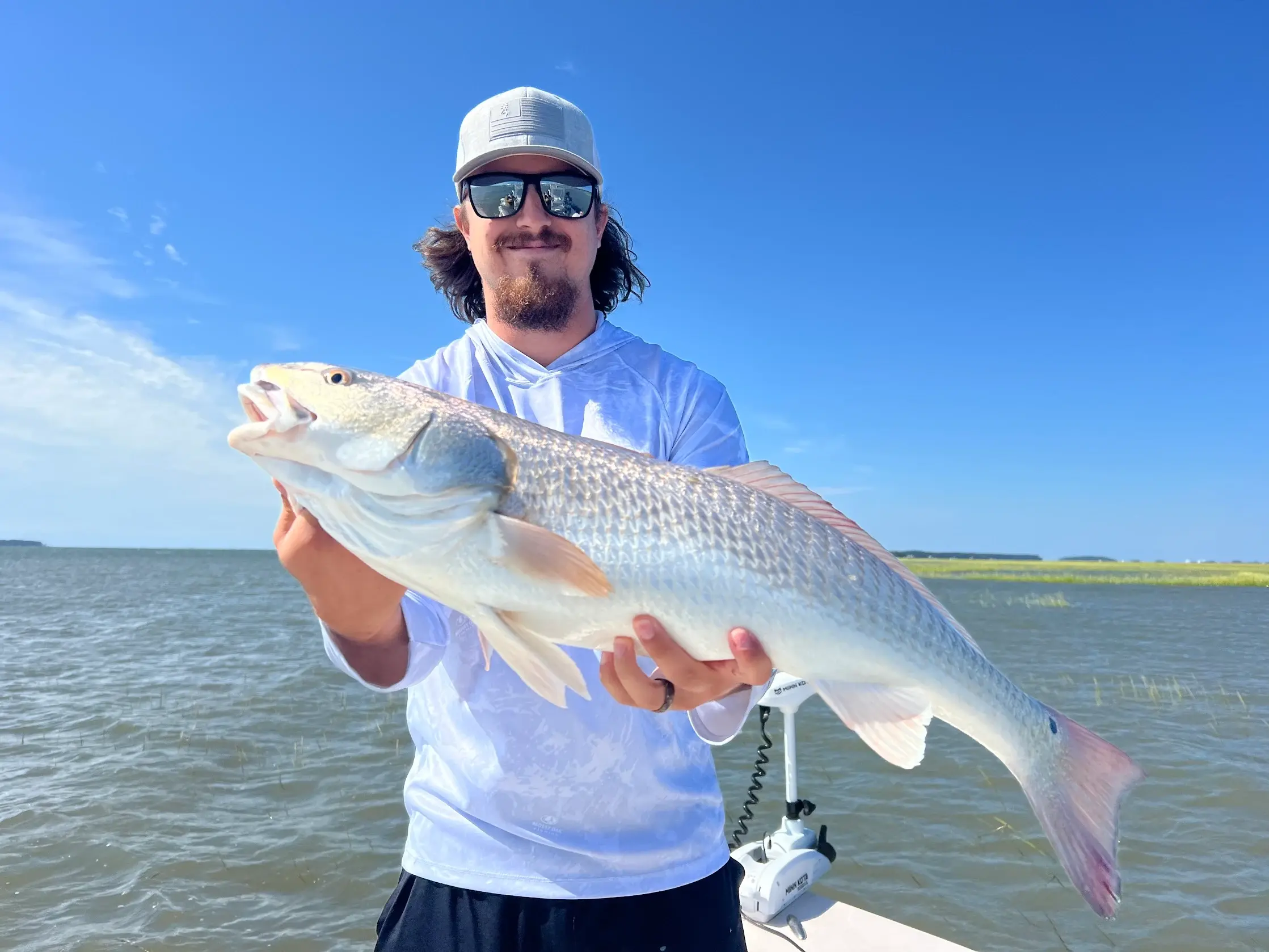 man shows off a fish on a boat