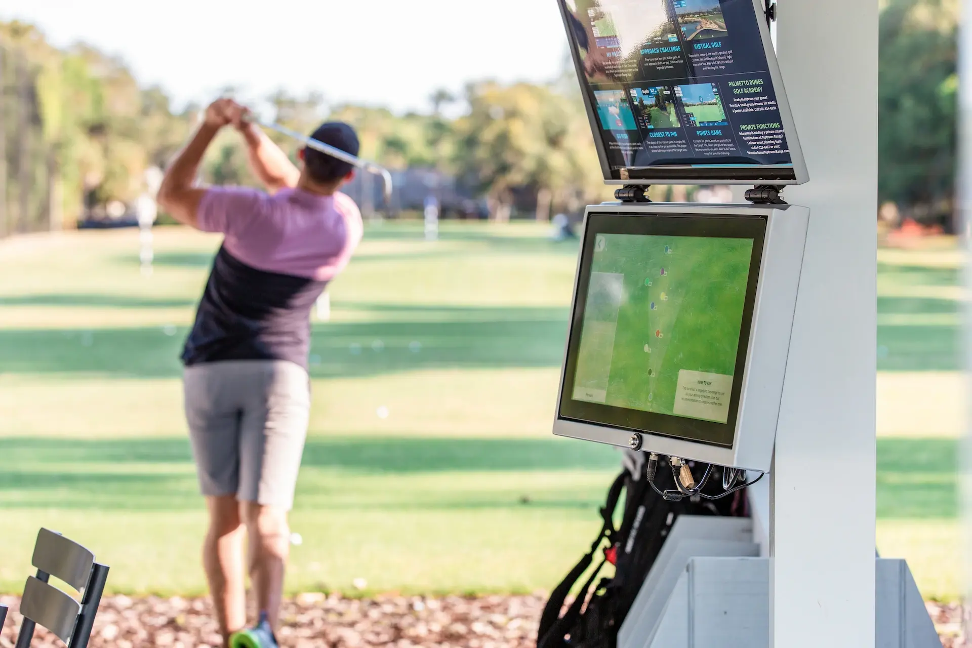 male golfer post swing at Toptracer driving range with Toptracer screen and technology in the forefront
