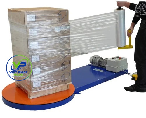 Warehouse worker hand-wrapping a pallet with stretch film