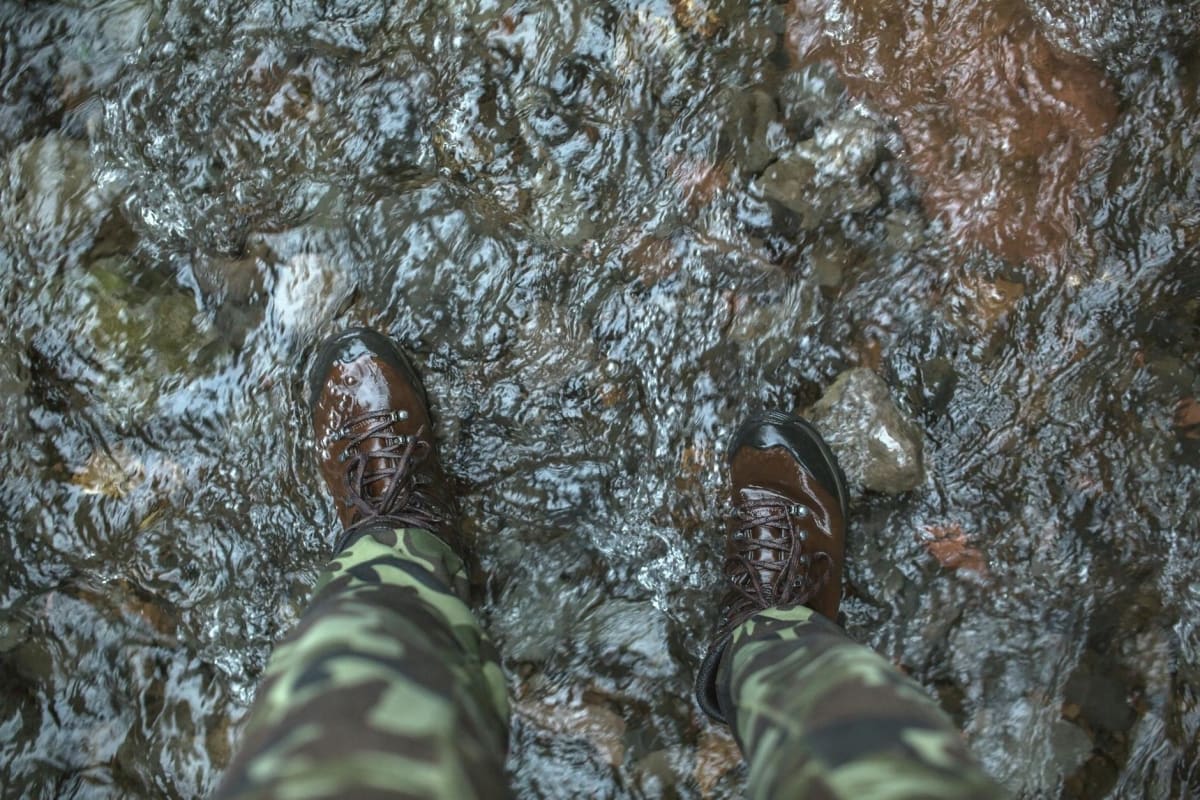 hiking boots trekking poles mountain stream crossing summer