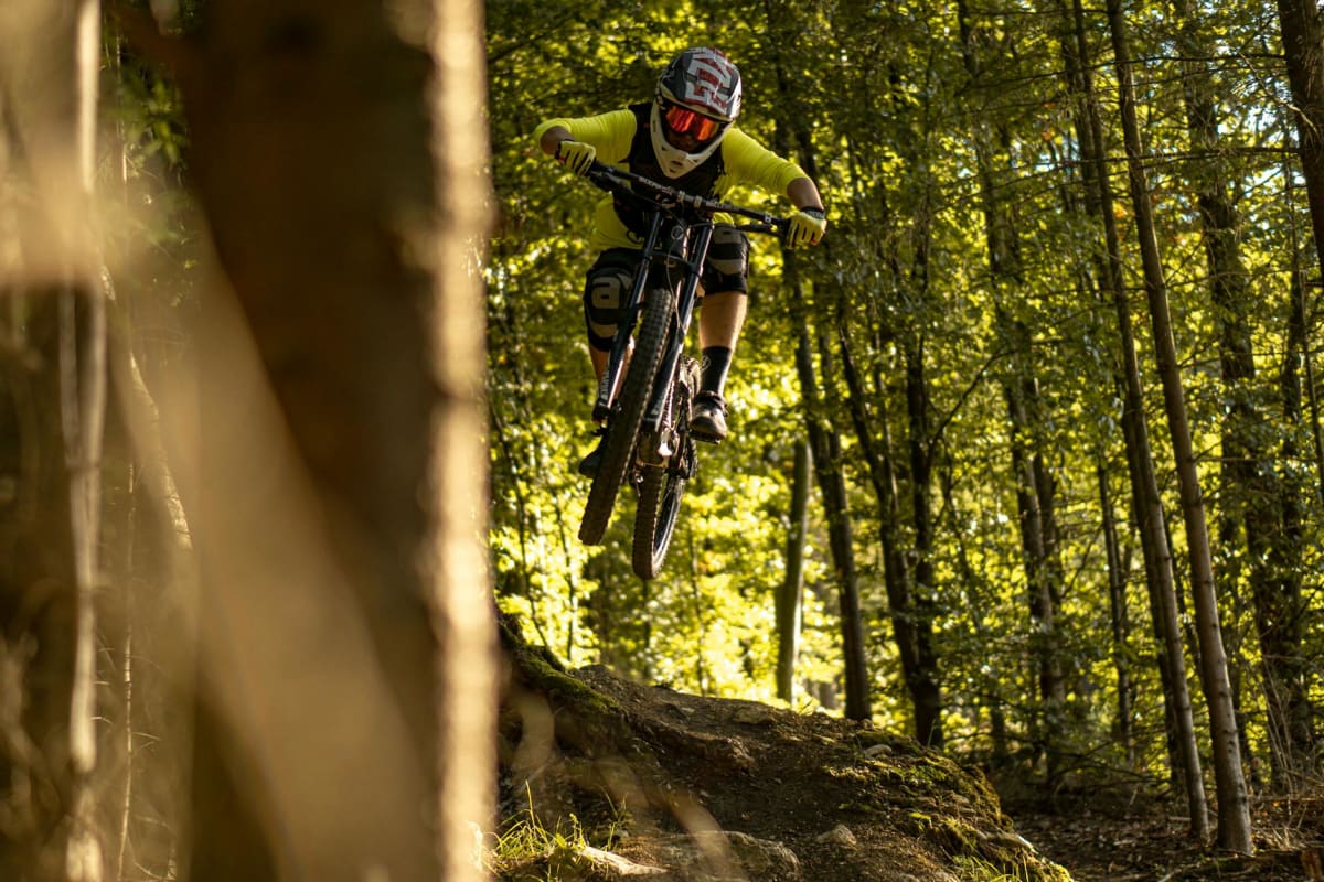Mountain biker jumping over rocky terrain alpine forest