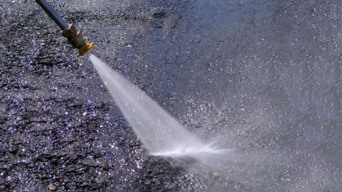 Power washer cleaning asphalt surface showing before and after results