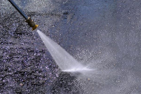 Power washer cleaning asphalt surface showing before and after results