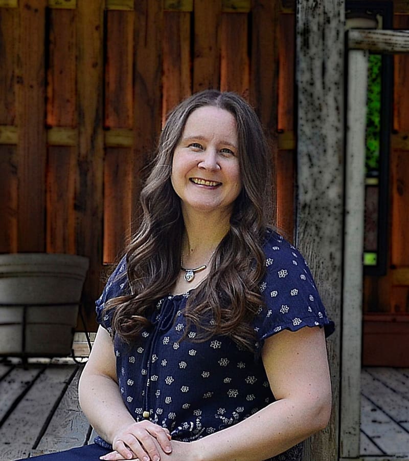 Studio Musicale music teacher smiling outdoors against a wooden fence backdrop.