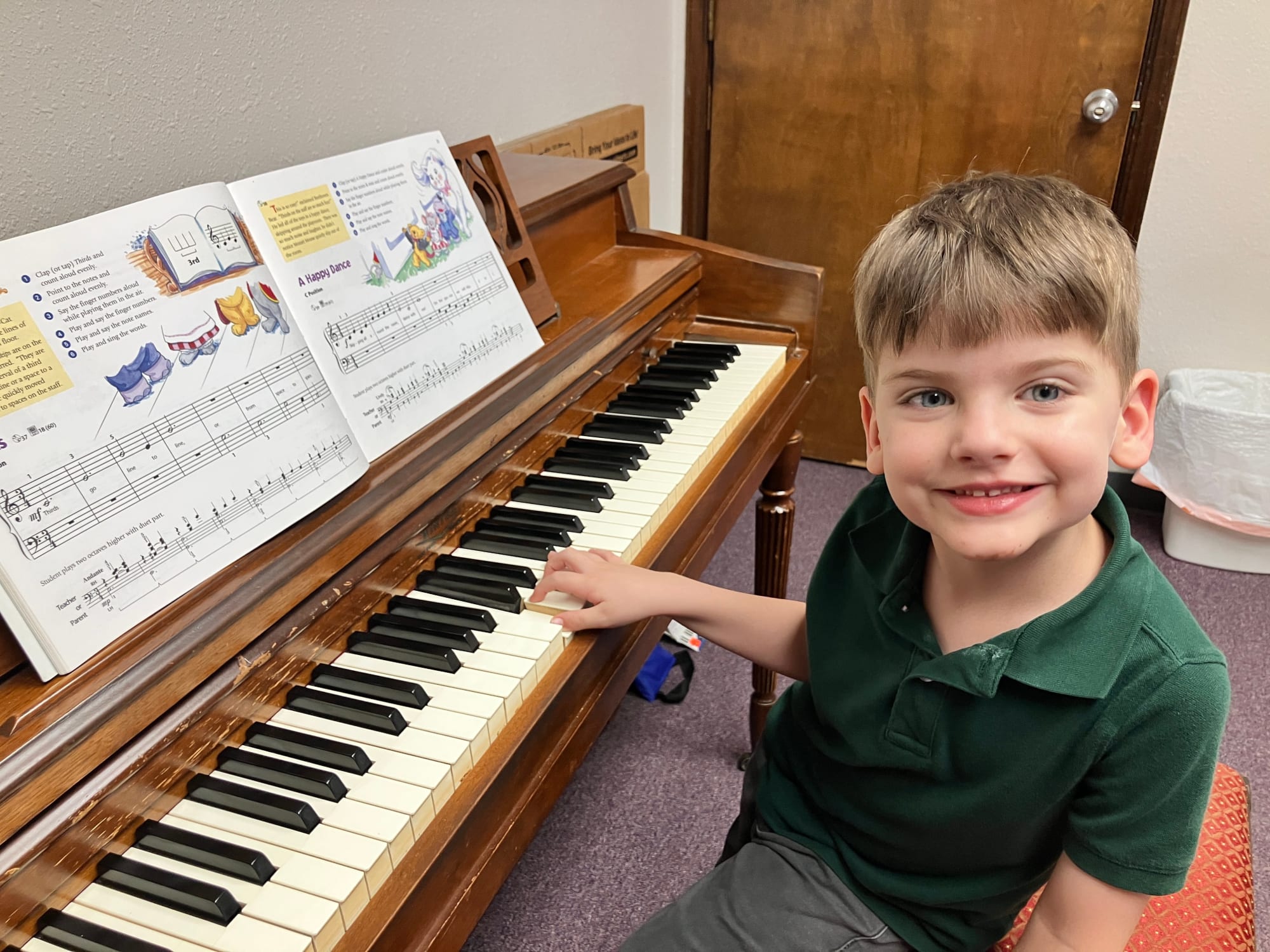 Young student smiling at piano while playing from sheet music during a lesson at Studio Musicale.