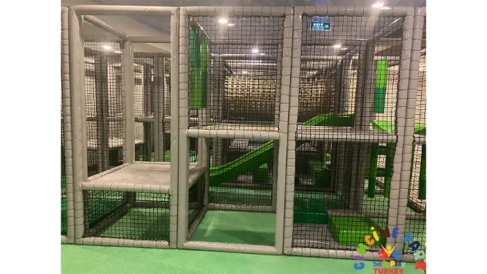 Çocuklar için güvenli ve eğlenceli, yeşil kaydırak ve tırmanma elemanları içeren gri ve yeşil soft play alanı detayı.