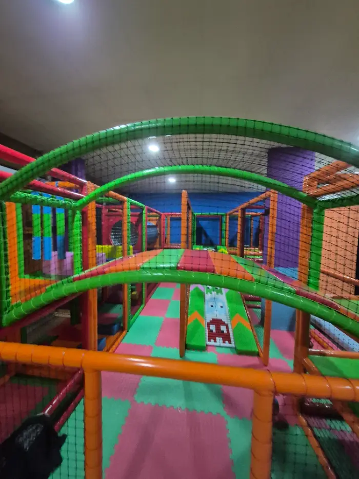 Çok katmanlı, renkli boru tünelleri ve güvenlik ağlarıyla donatılmış geniş bir iç mekan soft play alanı genel görünümü.
