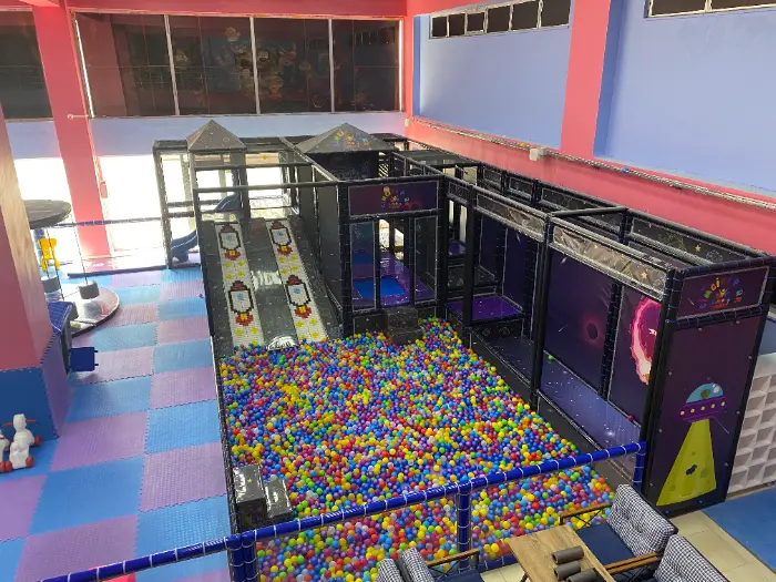 An overview of the soft play system, with a large ball pool, spacecraft and astronaut detailed wall panels, floor tiles in blue and purple.