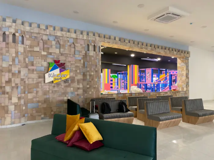 "Kinder Park" logosu ve kaleye benzeyen taş duvar tasarımıyla, aileler için konforlu bekleme alanı.