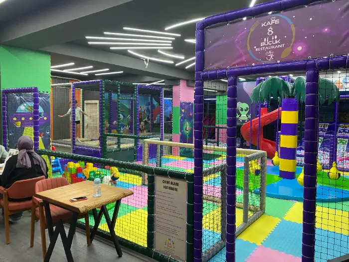 Children's entertainment center with purple-green space-themed, spiral slide and multi-storey soft playground, colorful floor mats and family cafeteria we produce in Antalya Cimcime Park.
