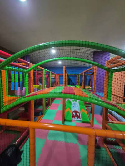 Çok katmanlı, renkli boru tünelleri ve güvenlik ağlarıyla donatılmış geniş bir iç mekan soft play alanı genel görünümü.