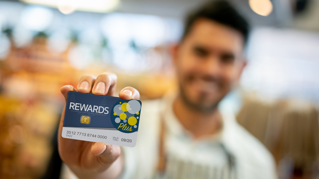 Happy vendor holding a Cash Rewards card for loyal customers
