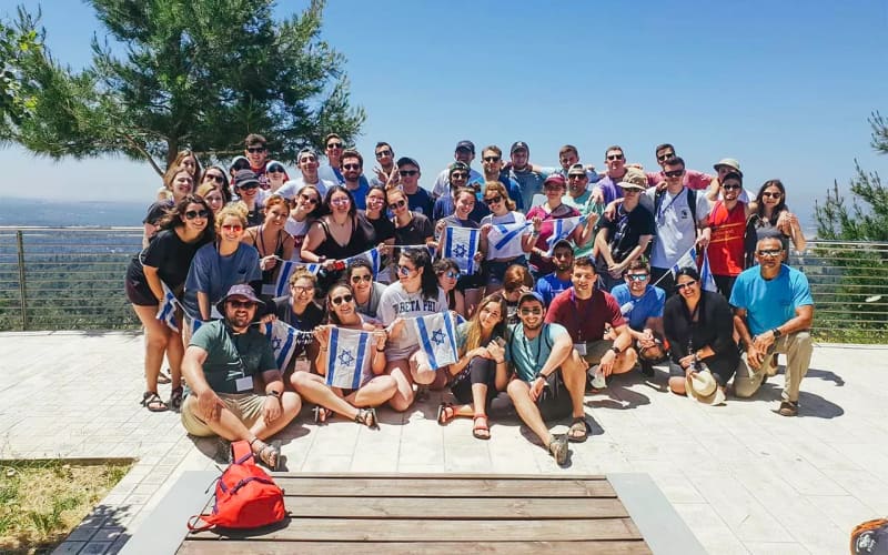 Cooper Myers with his 2019 Birthright Israel group holding Israeli flags