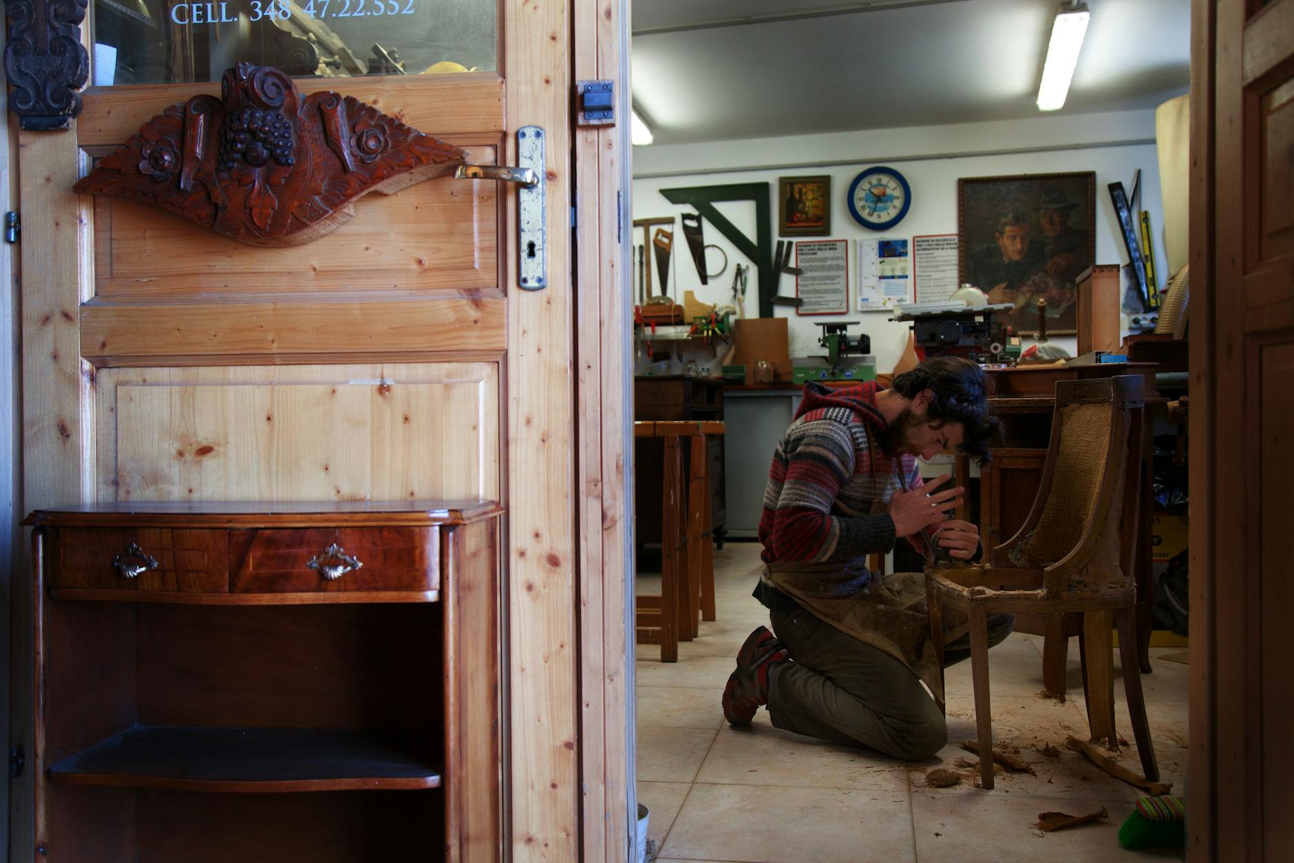 Artisans performing wood restoration techniques during a workshop, with tools and restored furniture pieces visible