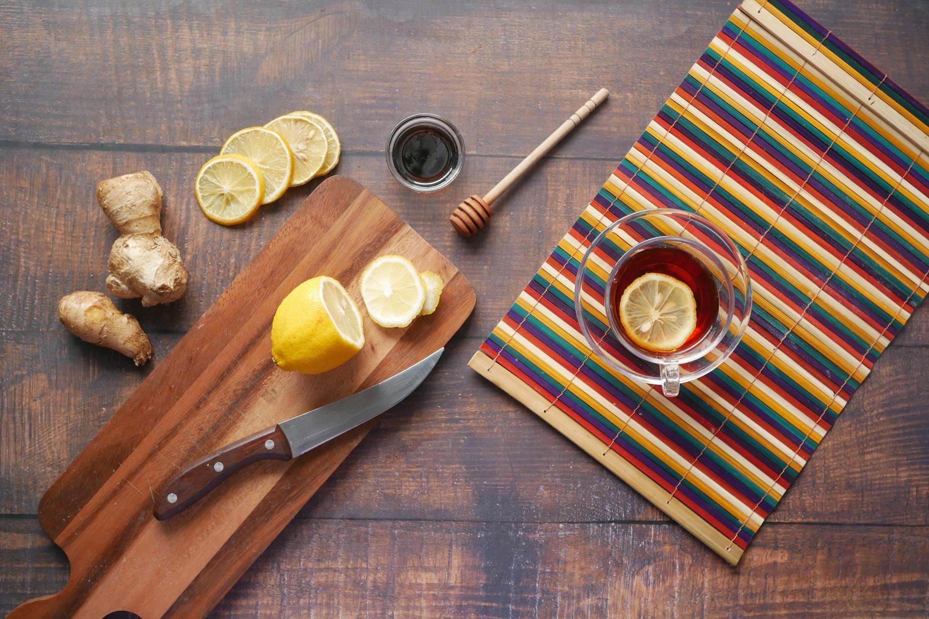 Collection of natural ingredients for wood furniture restoration including olive oil, beeswax, vinegar, lemon, and soft cloths arranged on a wooden surface