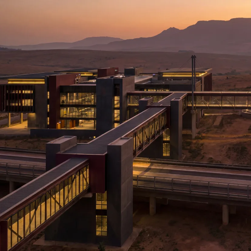 A large network of interconnected buildings and illuminated elevated passages at dusk.