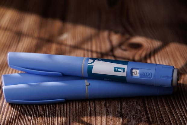 two blue weight loss injection pens on a wooden tabletop