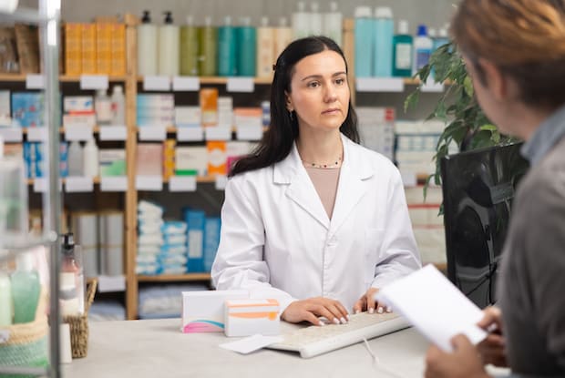 a pharmacist behind a counter speaking with a customer