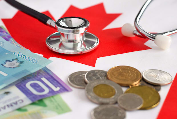 Canadian cash and coins, stethoscope, on a Canadian flag
