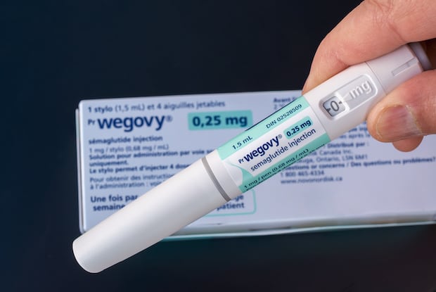 a Wegovy pen being held up by a patient's hand