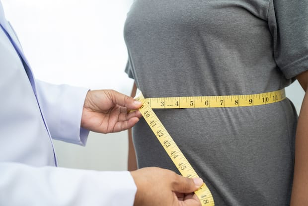 a patient being measured to determine their BMI and whether they are considered obese