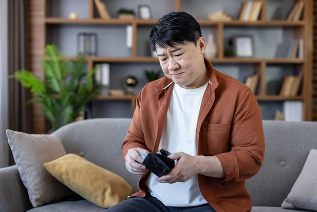 a distraught-looking man checking his wallet