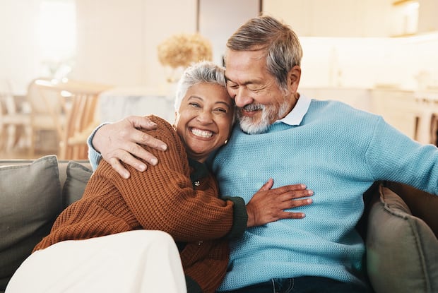 an older couple sitting and laughing together on a sofa