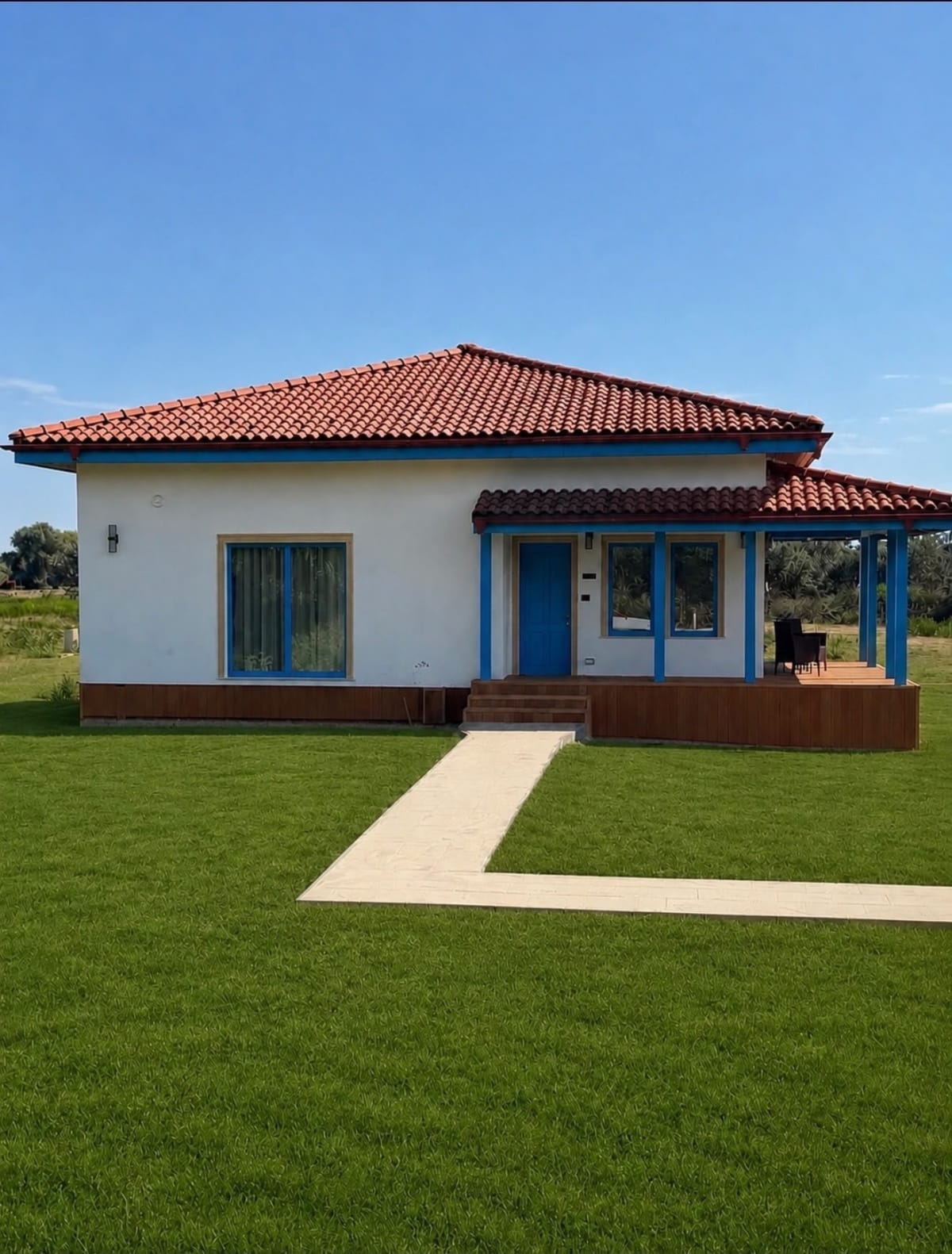 Casă de vacanță Delta Balamuc: acoperiș din țiglă, tâmplărie albastră și terasă din lemn, în mijlocul gazonului