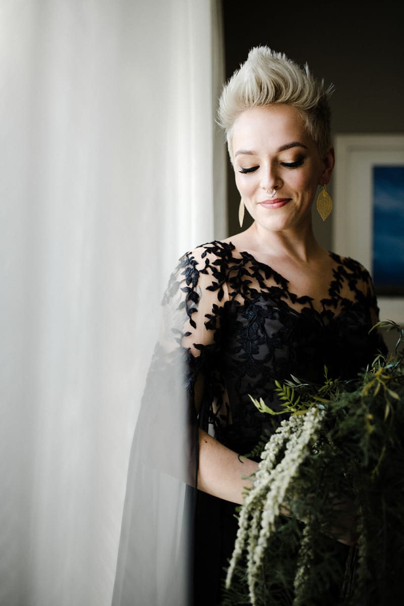 Bride holding a bouquet in a long-sleeve black lace wedding dress