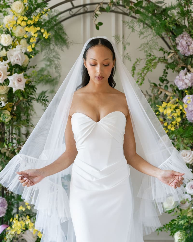 The Bride wear a veil is a two-tier ruffled design made of sheer tulle.