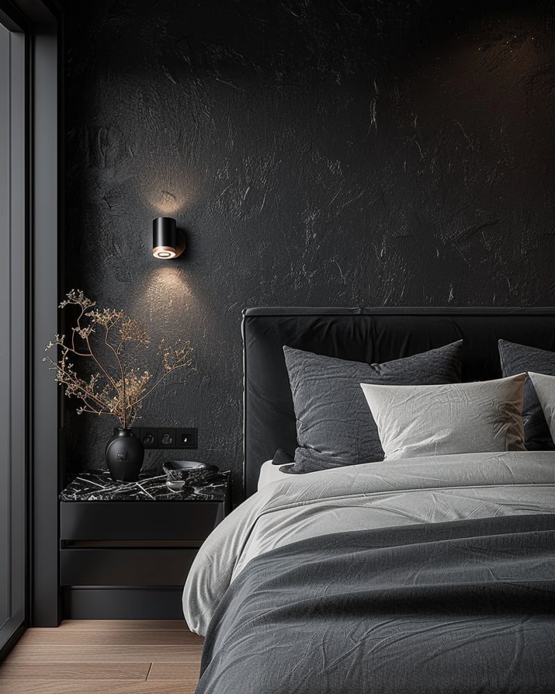 Minimalist dark bedroom with textured black walls, modern sconce lighting, marble nightstand, grey bedding, and monochrome design