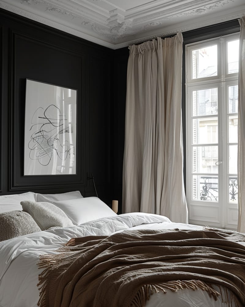 Parisian dark bedroom featuring ornate crown molding, matte black walls, white linen bedding, abstract art, floor-length curtains, French windows, brown throw, monochromatic design