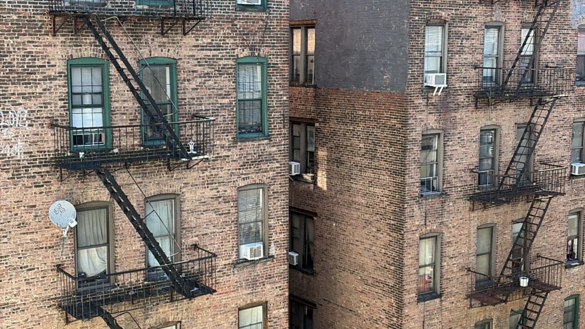 Brick rear facades of two apartment buildings covered in zigzagging fire escapes and satellite dishes