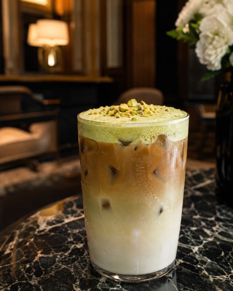 Latte gelado de pistache com camadas visíveis de leite e café sobre gelo