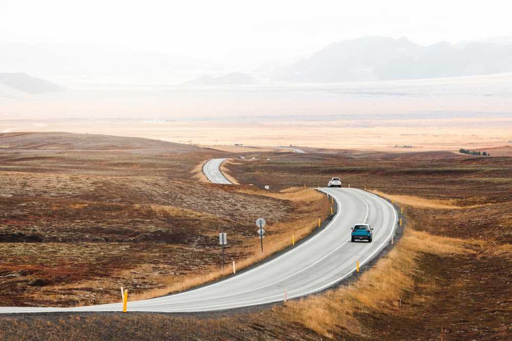 Cars driving along a quiet Iceland road through autumn landscapes