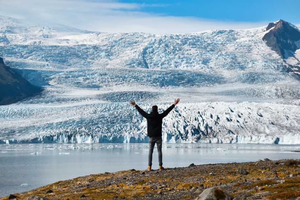 Traveler standing in front of a glacier and icy lagoon in Iceland
