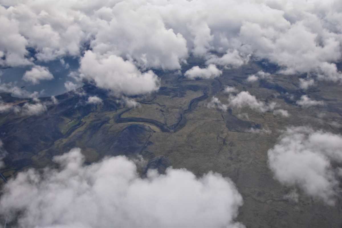 Aerial view of Icelandic lava fields and rivers seen through low clouds.