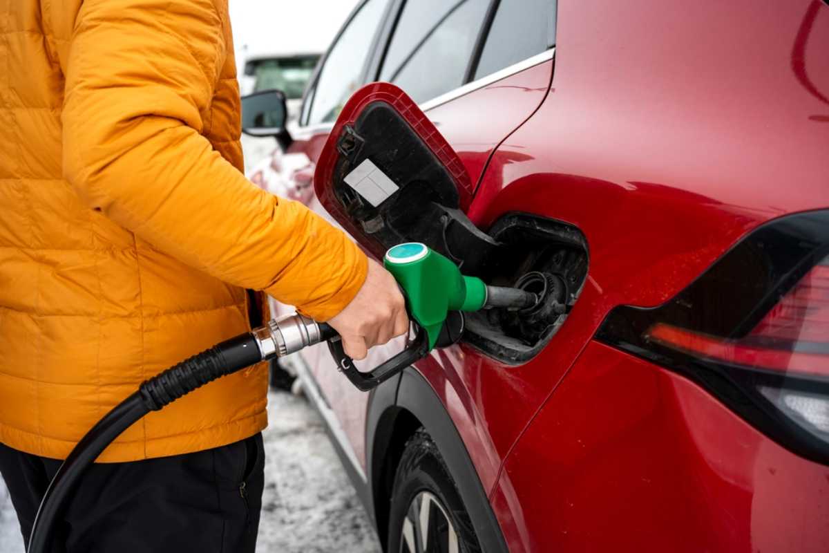 Traveler refueling a red rental car at a gas station in Iceland.
